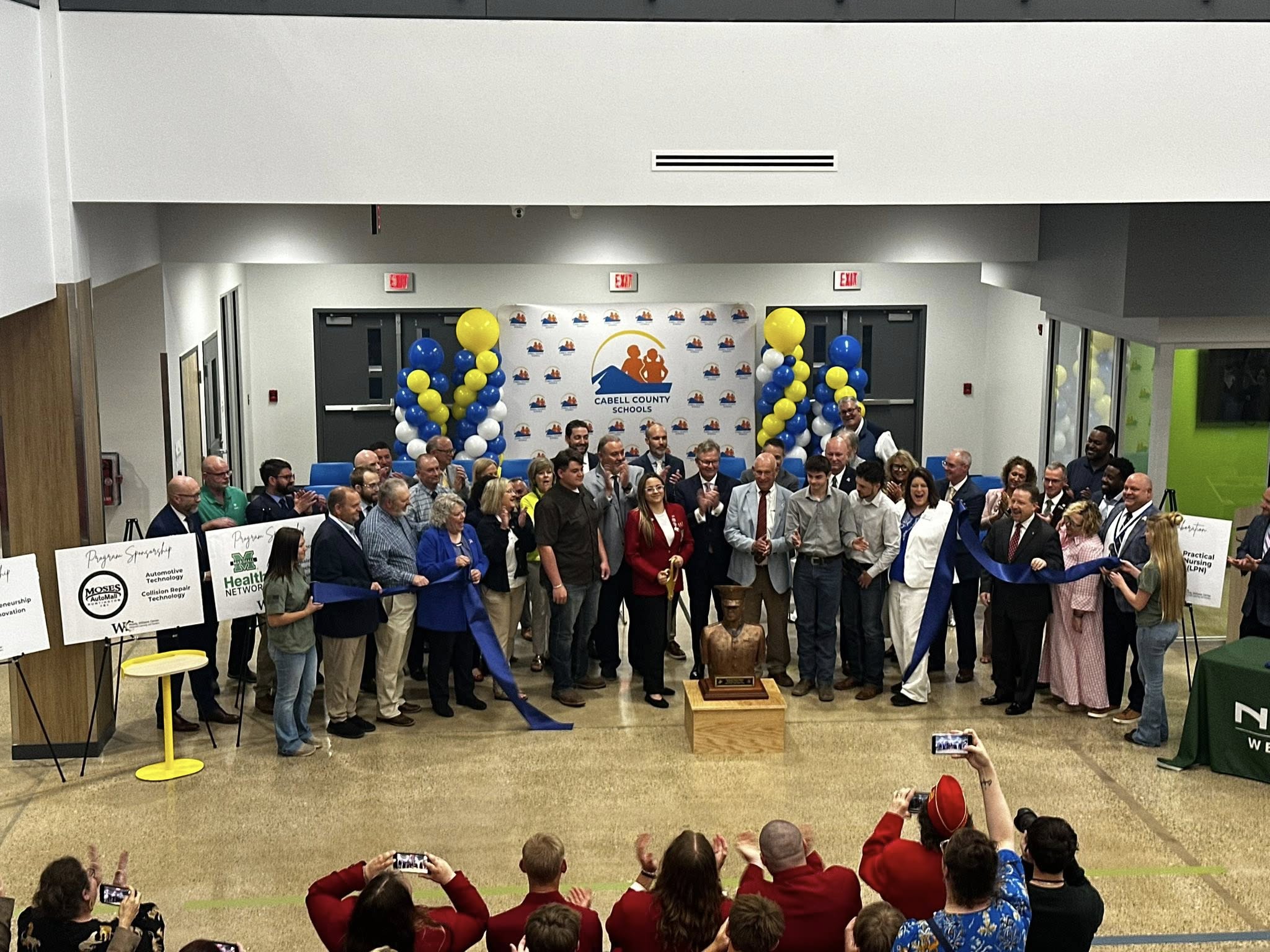 a group of students, staff, and community leaders gather to cut the ribbon inside the Woody Williams Center for Advanced Learning and Careers